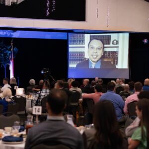 Dinner Attendees watching Roger Severino on a screen