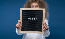 Girl holding a letter board with the word vote spelled out