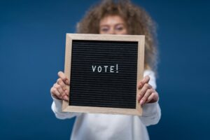 Girl holding a letter board with the word vote spelled out